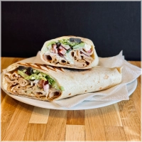 Dürüm gevuld met döner, knoflooksaus, sla, komkommer, tomaat, ui en fetakaas